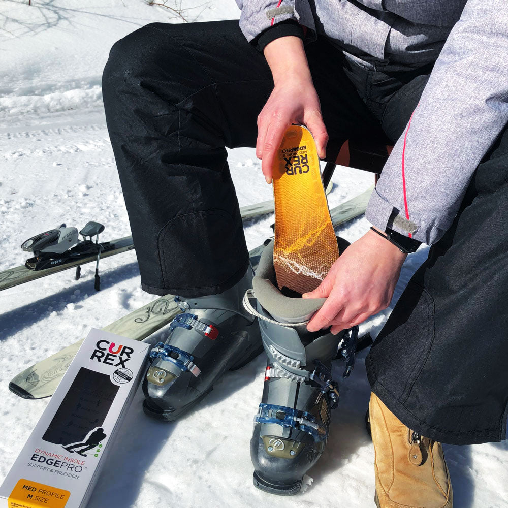 Man sitting on chair next to skis preparing to go skiing by adding CURREX EDGEPRO yellow medium profile insoles to ski boots #1-wahle-dein-profil_med