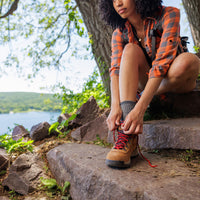 Woman taking a break from hiking to tie hiking shoe #1-wahle-dein-profil_high